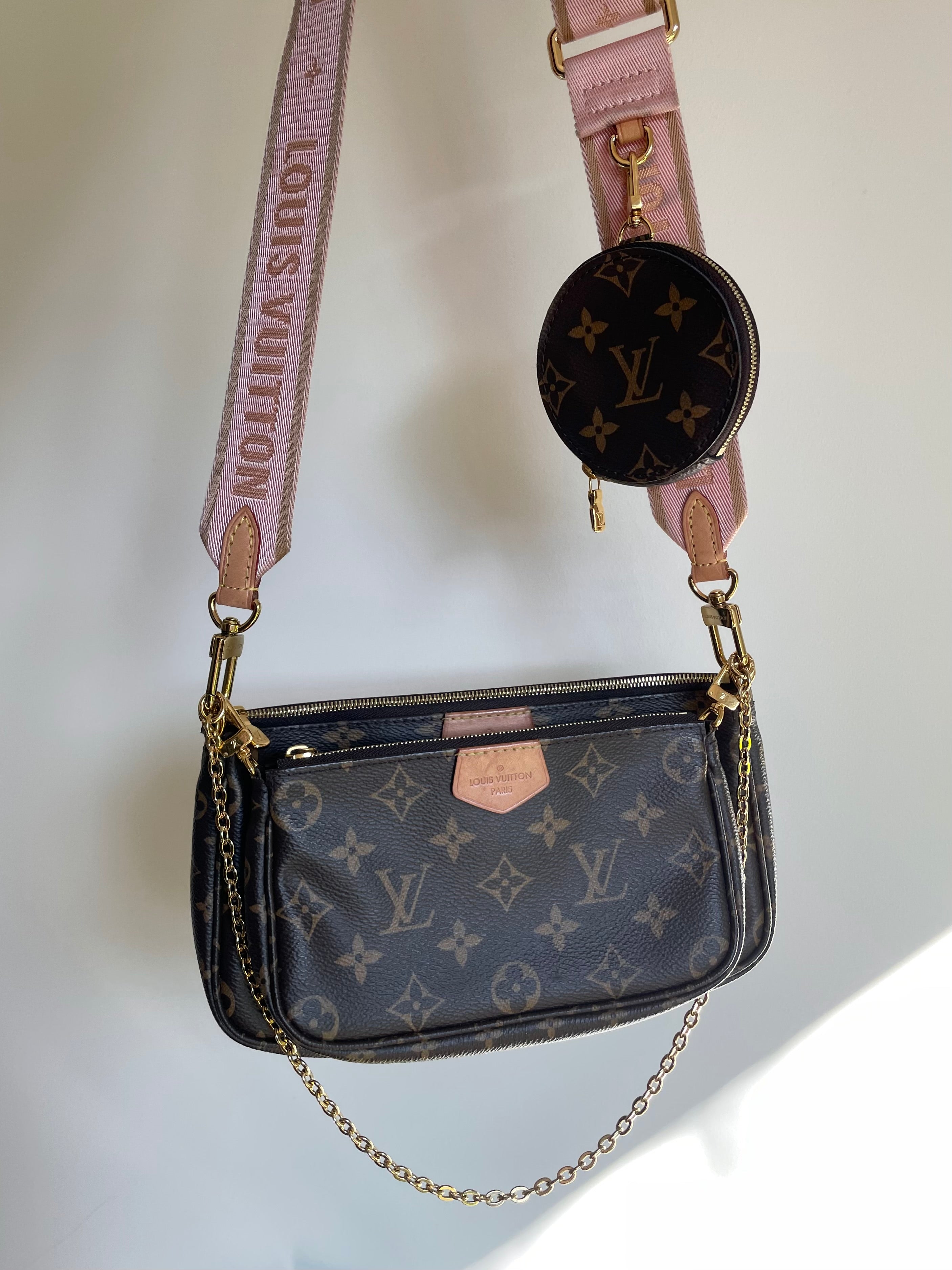 Louis Vuitton Multi Pochette Accessoires handbag with monogram pattern and pink strap on a light background